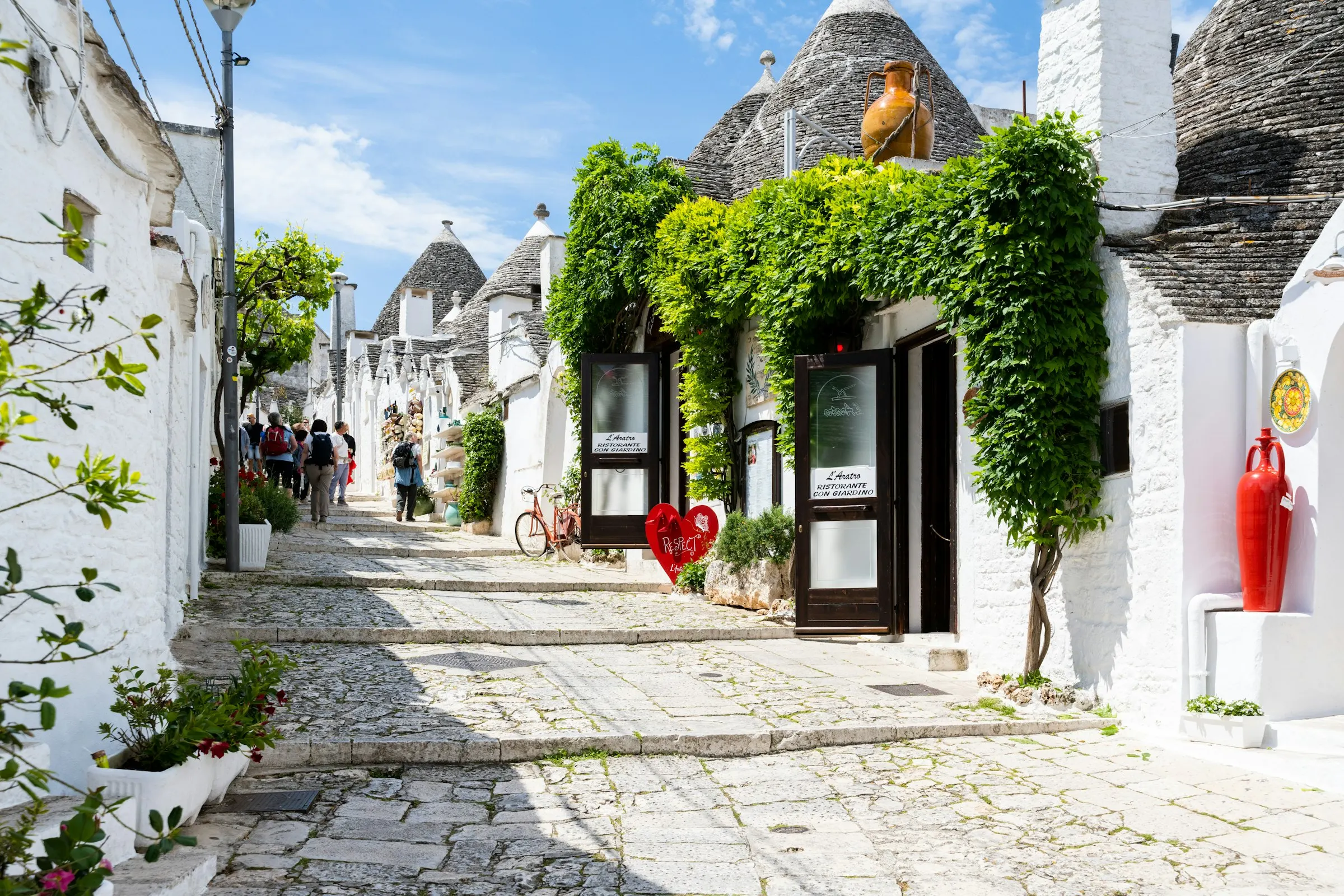 A narrow street of whitewashed trulli houses with green vines in Puglia, Italy